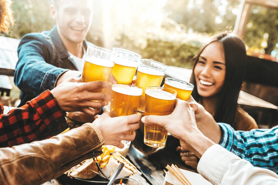 group of friends at a brewery eating burgers and drinking beers together outside